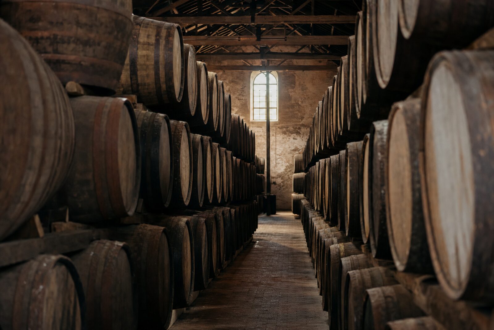 Oak casks maturing in a traditional wine and spirits warehouse.